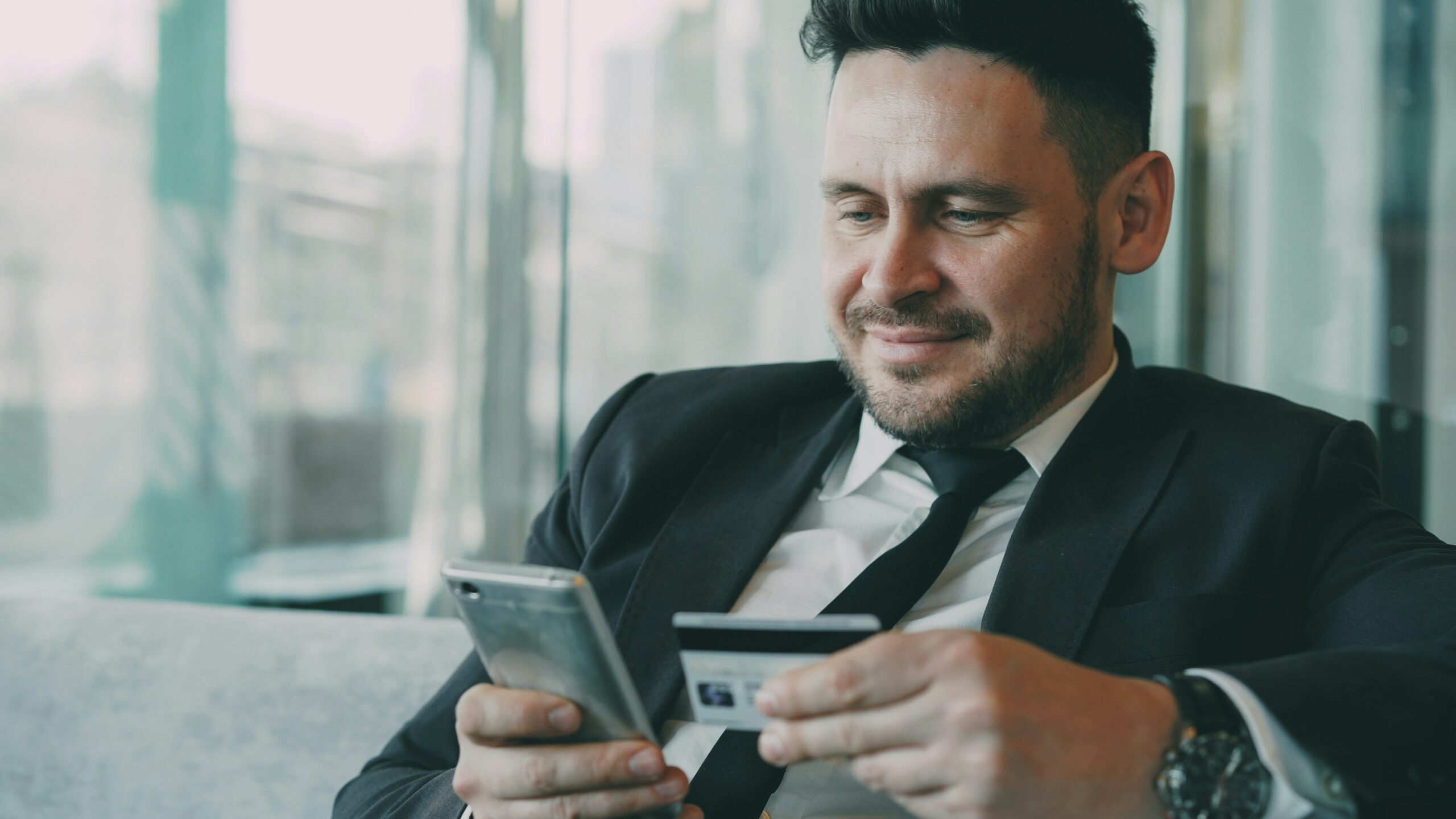 man in suit using smartphone and credit card