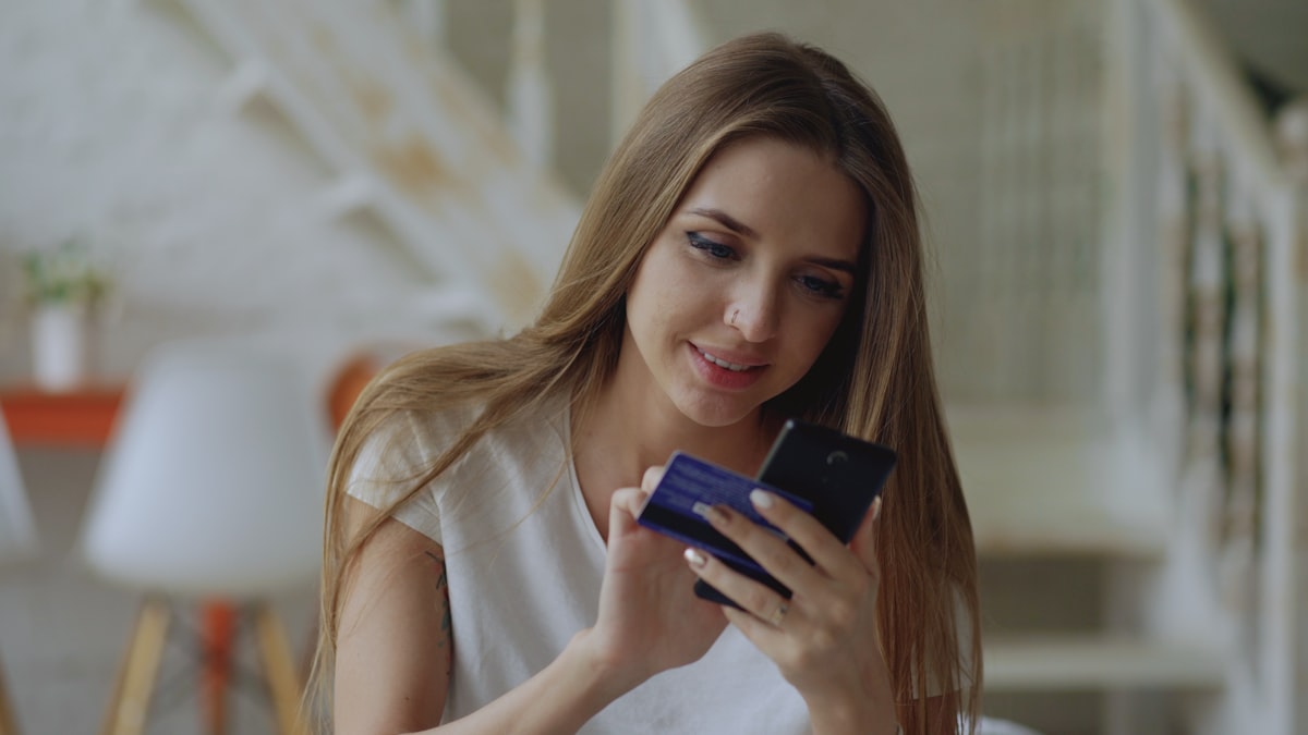 Woman holding credit card and smartphone — digital financial services and mobile banking in 2026
