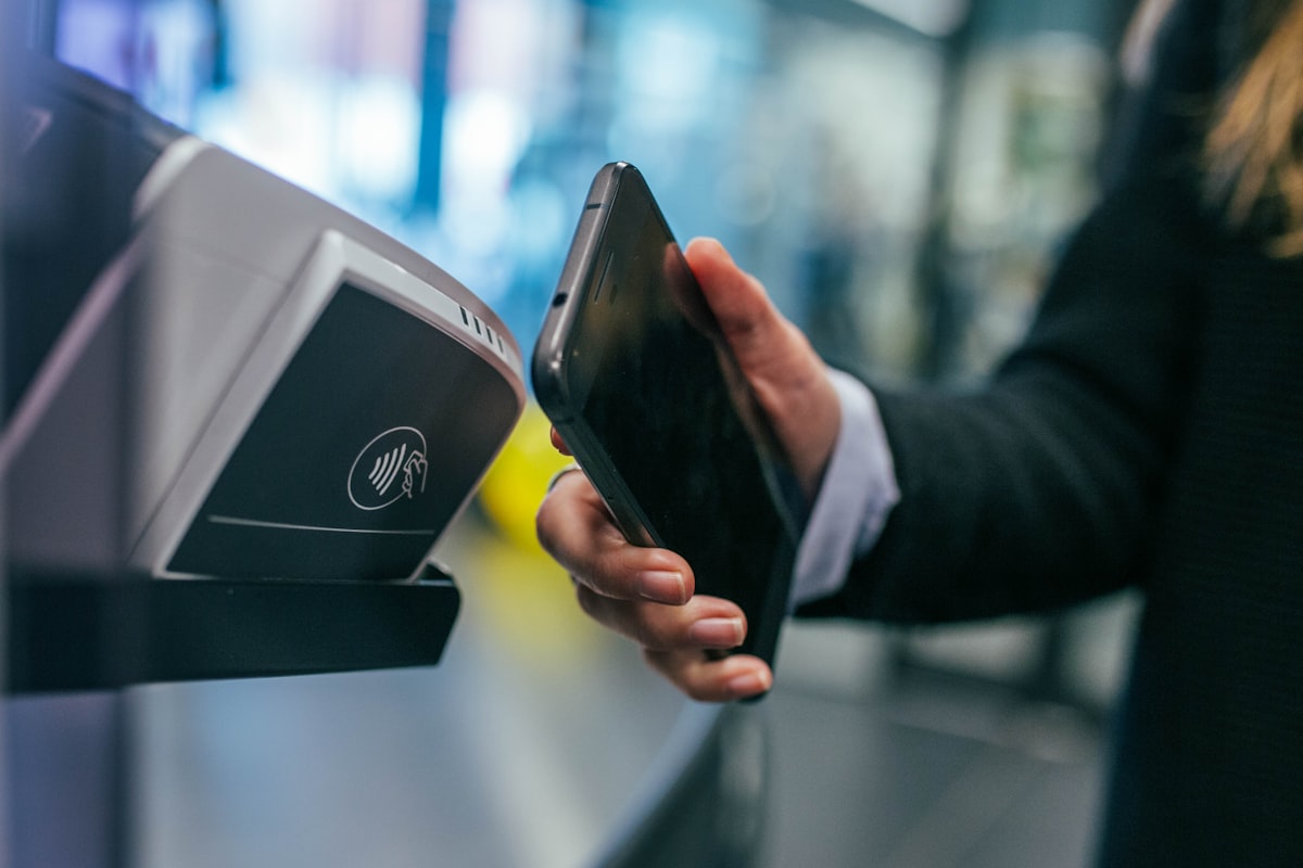 Pessoa realizando pagamento via celular em terminal de pagamento — mobile payment e fintech em ação