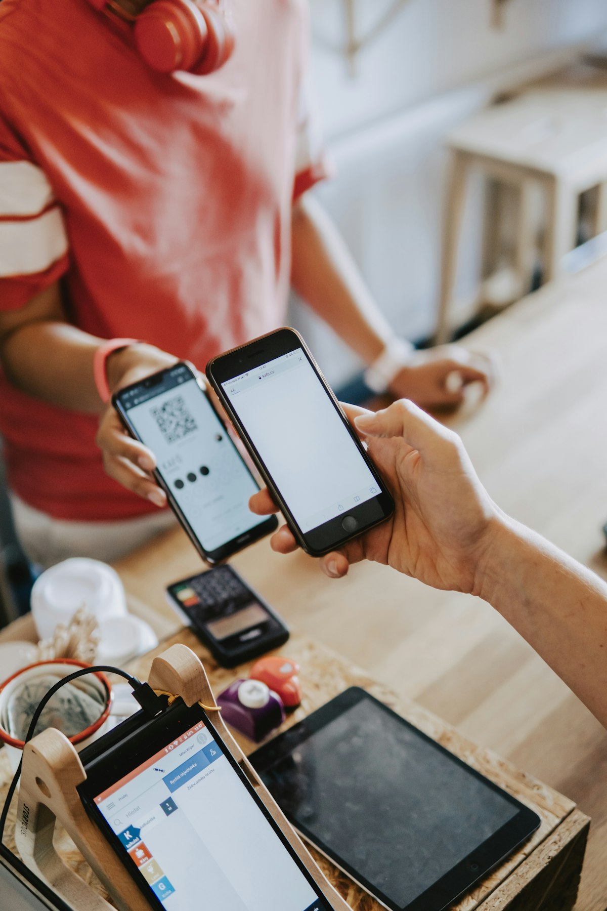 Two hands holding smartphones side by side, screens lit up, representing digital payment and platform connectivity