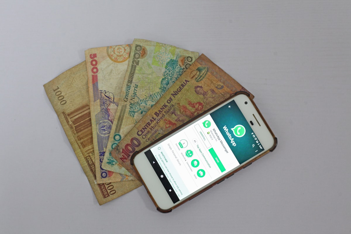 Smartphone com aplicativo bancário ao lado de notas de dinheiro, representando serviços financeiros digitais